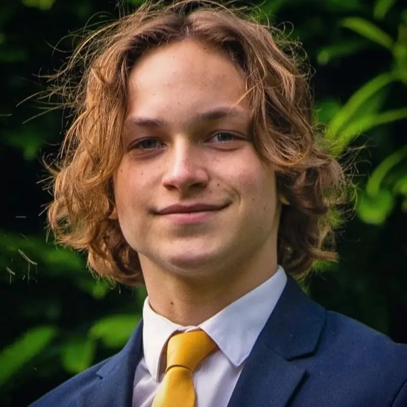 Charlie Cook wearing a suit and yellow tie outdoors